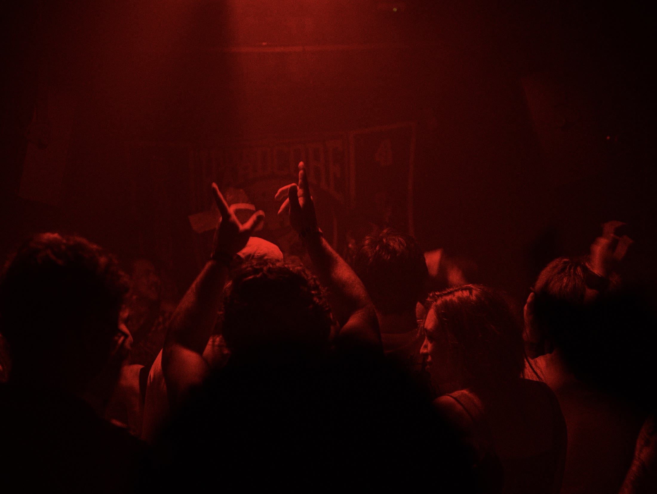 Hard Signal crowd with hands raised under deep red club lights